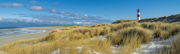 istock Red and white Lighthouse on sand dune in snow, Island Sylt, Germany 936580726