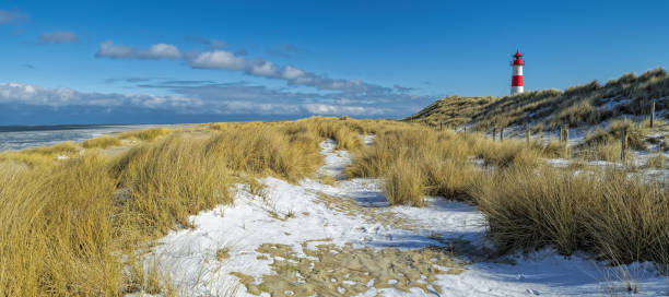 istock Red and white Lighthouse on sand dune in snow, Island Sylt, Germany 936580988