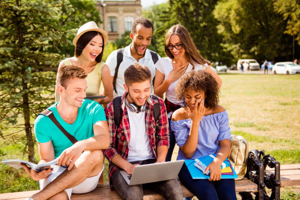 istock It`s so fun and easier together! Six happy multi ethnic students are learning outdoors in a sunny park, with books, note pads and devices, dressed comfortable, laughing 936581178
