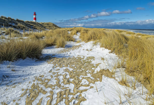 istock Red and white Lighthouse on sand dune in snow, Island Sylt, Germany 936581232