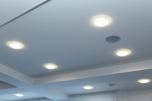 Modern layered ceiling with embedded lights and stretched ceiling inlay, lights on.