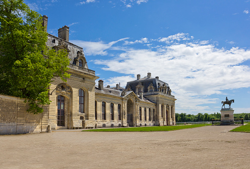 Chantilly, France - May 16, 2017: Great Stables of Domaine de Chantilly with equestrian statue of Henri d'Orleans, Duke of Aumale (sculptor Gerome, made in 1899)