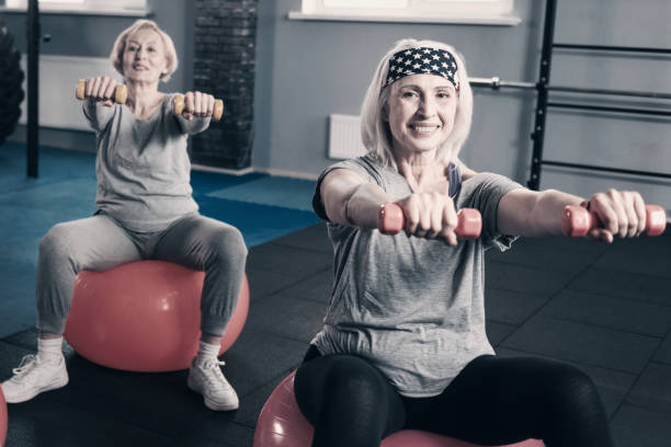 istock Two senior women stretching out hands with dumbbells 936602902