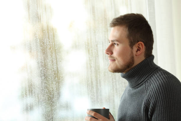 istock Happy man looking through a window in a rainy day 936604202