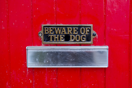 Beware of dog sign on large red house front door for home security