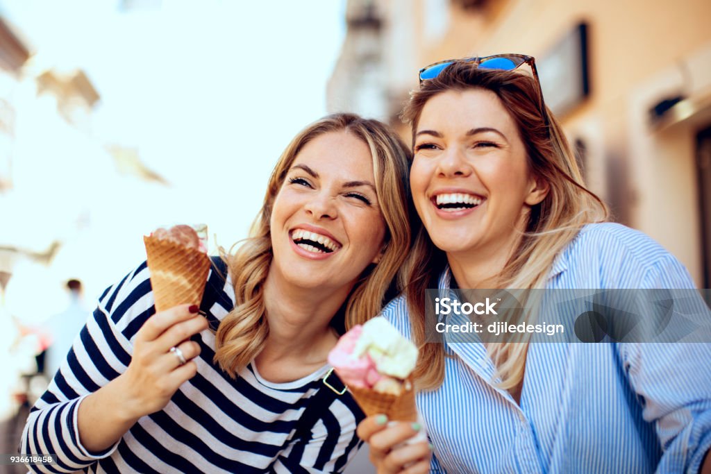 Deux jeunes femmes riant et la tenue de la crème glacée à la main - Photo de Crème glacée libre de droits