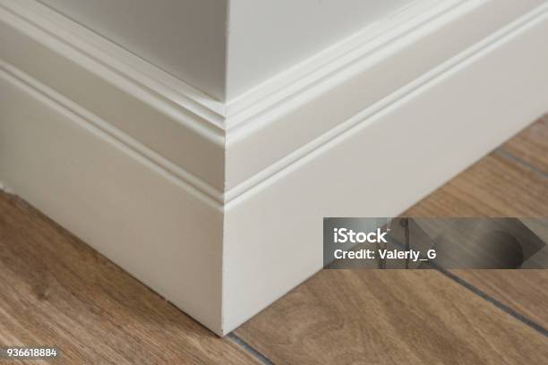 Molding In The Interior Baseboard Corner Light Matte Wall With Tiles Immitating Hardwood Flooring Stock Photo - Download Image Now