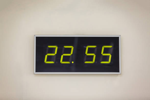 istock Black digital clock on a white background showing time 22 hours 55 minutes 936629592