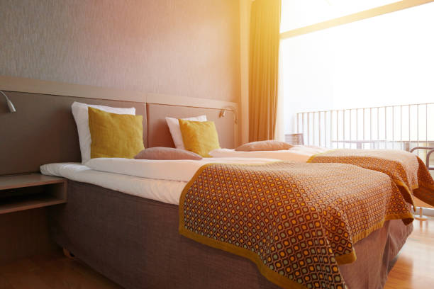 Tidy hotel room with pillows piled up. White sheets and pillows