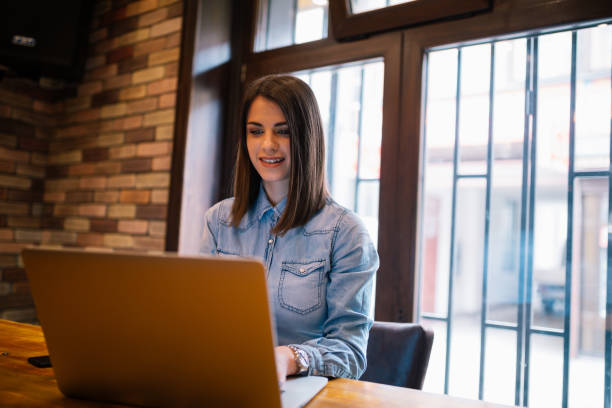 istock Attractive young woman working on a laptop computer in a coffee shop 936645704