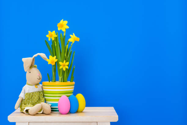 istock Easter bunny with yellow daffodils and easter eggs isolated on the blue background 936649820