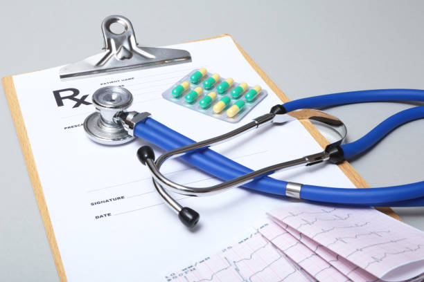 istock Stethoscope, red heart, RX prescription and assorted pills on white table with space for text. 936653302
