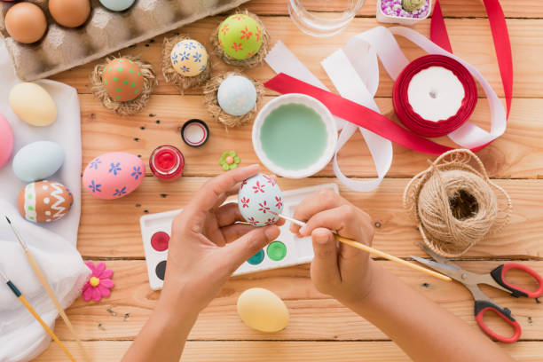 istock Happy easter! A woman hand painting Easter eggs. Happy family preparing for Easter. 936664974