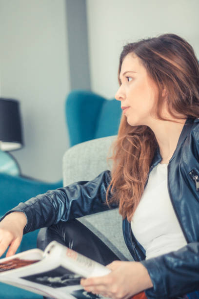 istock Beautiful woman thinking about something while reading magazine. 936693272