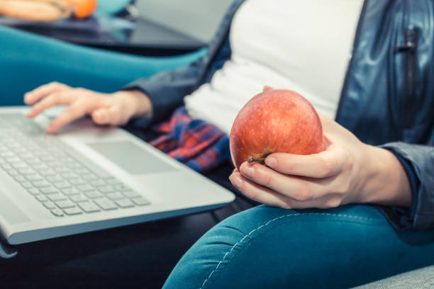 istock Close up of woman holding apple while using laptop. 936693476