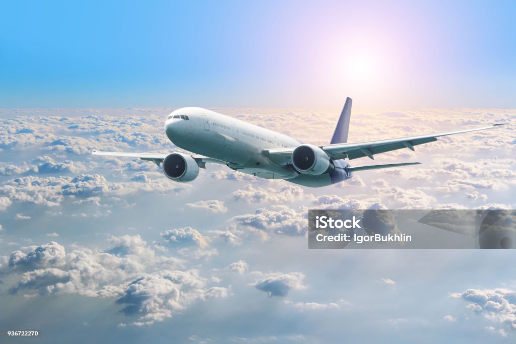 Passenger airplane flying above clouds. View from the window plane to amazing sky at the sunset. Air company. Airline. Boing 747,picturesque view through window, jet flying at the sunset. Airplane Stock Photo
