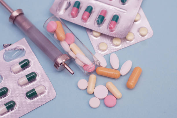 istock Colored Pills, Tablets and Capsules Blisters for Pharmacy and Medicine, with a Syringe. Healthy and medicine concept. Blue Background. 936738708