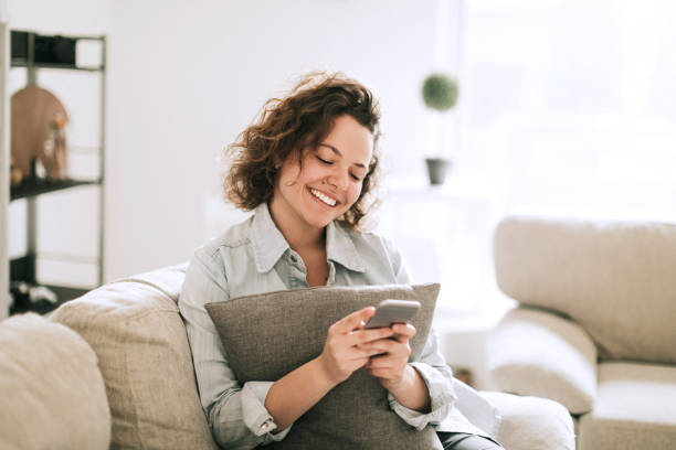 istock Young woman texting from living room 936738810