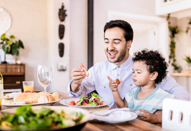 Father and son having healthy food at table in house