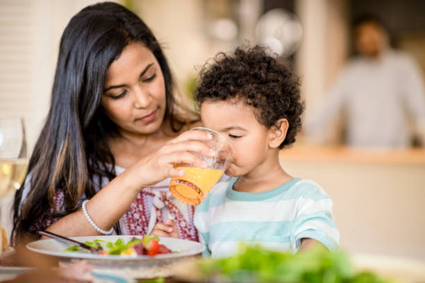 istock Mother feeding juice to son during lunch at table 936749546