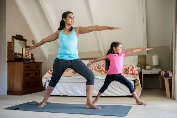 istock Mother and daughter practicing yoga in bedroom 936749850