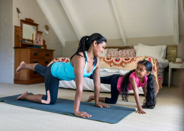 istock Mother and daughter exercising in bedroom 936749866