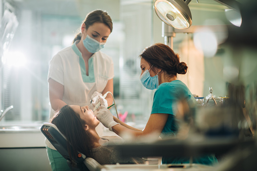 Dentista y su asistente realizar el taladrado dental en mujer joven. photo