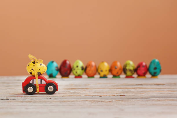 Easter holiday concept - Red toy car carrying yellow egg. stock photo