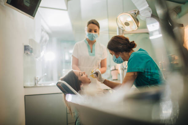 jeune femme ayant ses dents vérifiés au cabinet du dentiste. - dental assistent photos et images de collection