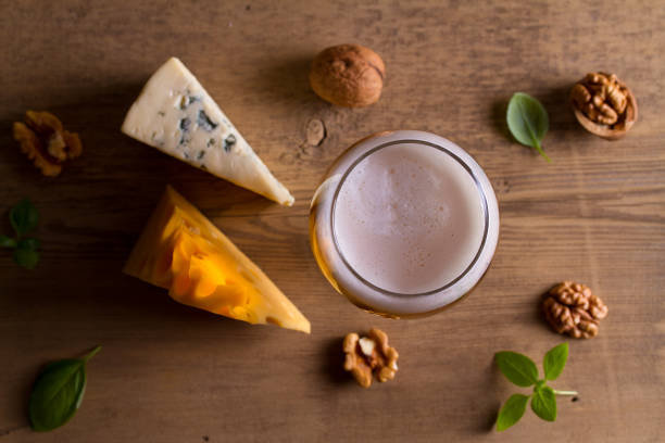 cerveja e queijo. copo de cerveja com queijo, nozes e manjericão sobre fundo de madeira - english walnut - fotografias e filmes do acervo