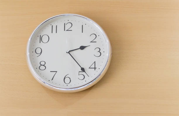 istock white steel clock on light wooden wall 936776544