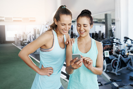 Shot of two young women using a cellphone at the gym