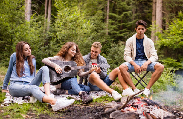 istock Teenagers wit a guitar camping in forest. 936800084