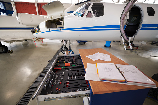 Private jet aircraft in the hangar open for regular maintenance service behind the toolbox and instruction manuals.