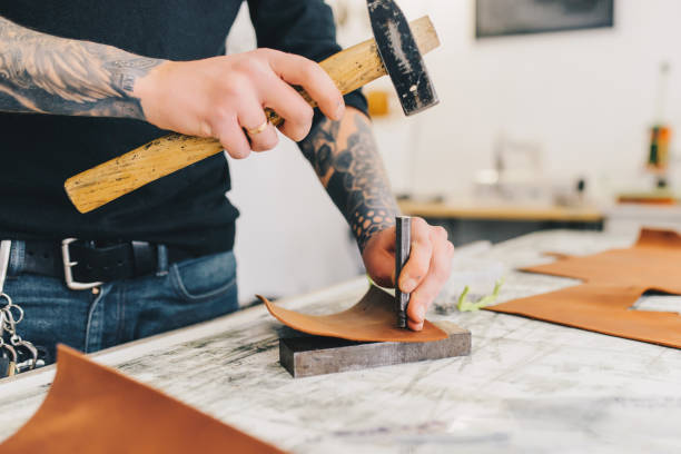 istock Close up of a leather craftsman working with leather using hammer. 936801806