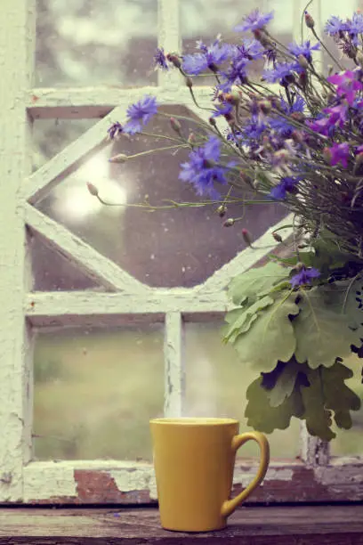 yellow mug and a large bouquet of wildflowers on the background of an old retro window