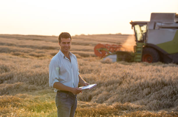 istock Engineer standing in field with combine harvester in background 936805734