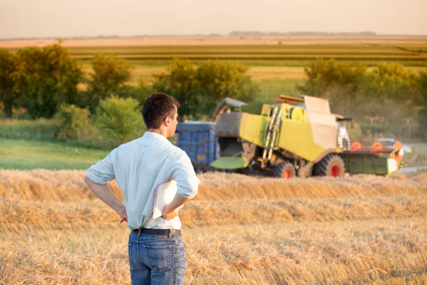 istock Engineer standing in field with combine harvester in background 936805806