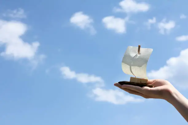Small sailing boat in hand against the sky with clouds