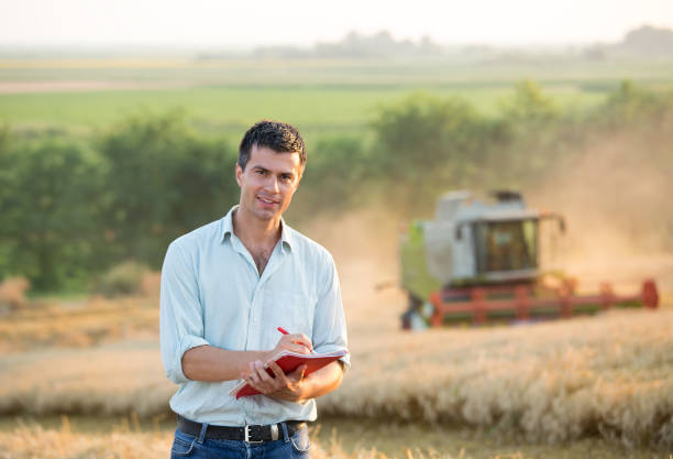 istock Engineer standing in field with combine harvester in background 936808246