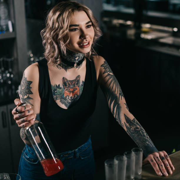istock tattooed bartender holding bottle of alcohol and looking away 936812152