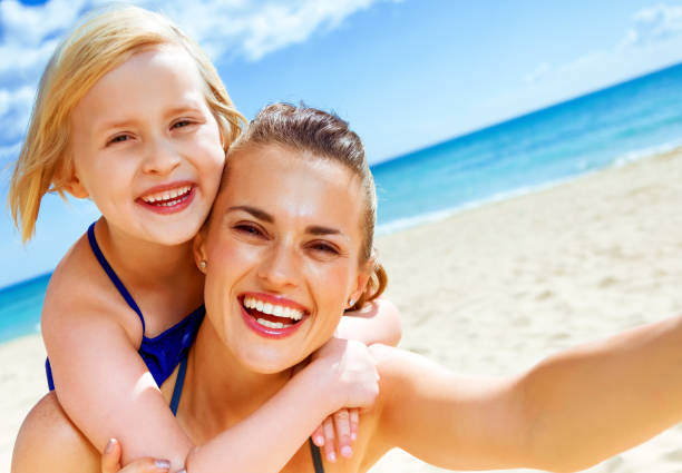 istock smiling young mother and child on seashore taking selfie 936812186
