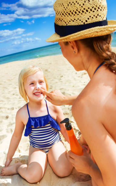 istock happy young mother and daughter on seashore applying SPF 936812302
