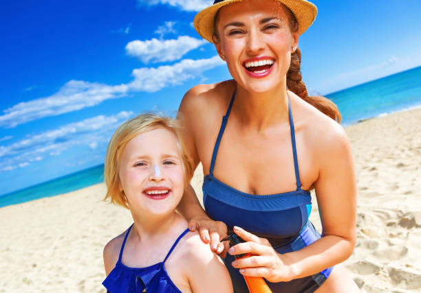 istock happy mother and child on seashore applying suntan lotion 936812362