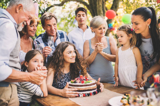 Family celebration or a garden party outside in the backyard. Family celebration outside in the backyard.Big garden party. Birthday party. A teenage girl with a birthday cake. birthday wishes for daughter stock pictures, royalty-free photos & images