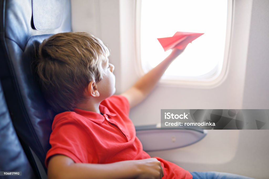 Kleine Kind Junge spielt mit rotem Papierflugzeug während des Fluges im Flugzeug - Lizenzfrei Flugzeug Stock-Foto
