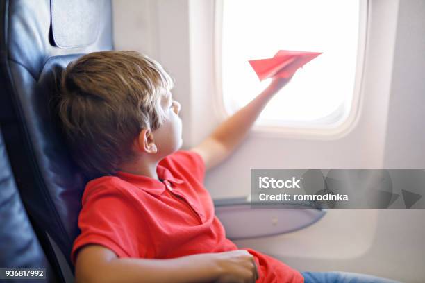 Kleine Kind Junge Spielt Mit Rotem Papierflugzeug Während Des Fluges Im Flugzeug Stockfoto und mehr Bilder von Flugzeug