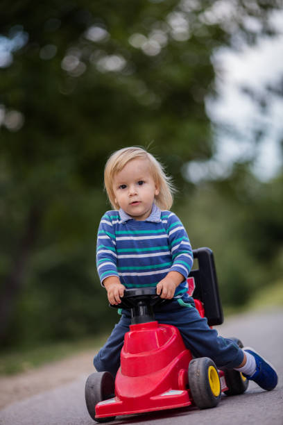 istock Small boy driving toy car vehicle and looking at camera. 936818156