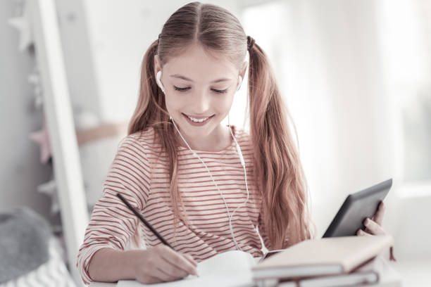 istock Exuberant girl writing and holding her tablet 936821028
