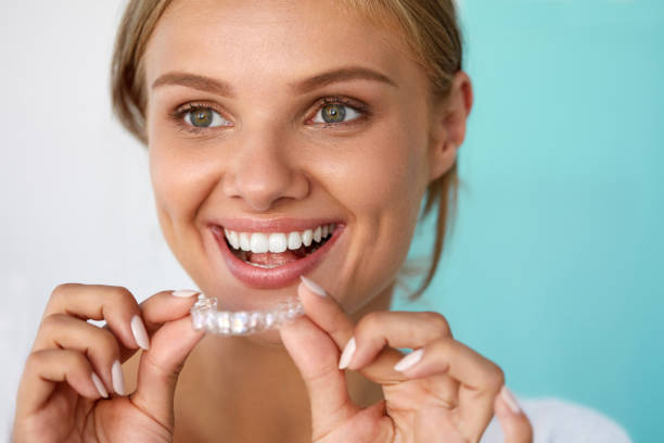 Smiling Woman With Beautiful Smile Using Teeth Whitening Tray Teeth Whitening. Beautiful Smiling Woman With White Smile, Straight Teeth Using Teeth Whitening Tray. Girl Holding Invisible Braces, Teeth Trainer. Dental Treatment Concept. High Resolution Image tooth whitening photos stock pictures, royalty-free photos & images